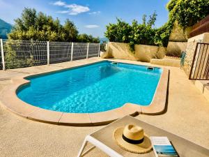 a swimming pool with a hat on a table next to it at Hôtel Villa Les Orangers in Olmeto