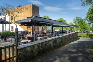 a restaurant with tables and umbrellas on a stone wall at Gran Camping Zarautz in Zarautz
