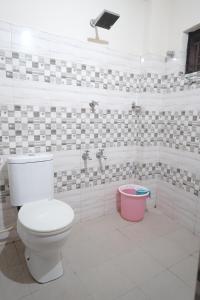 a bathroom with a toilet and a pink bucket at Nova Saara Palace in Kannur