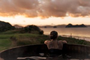 a woman sitting in a bath tub watching the sunset at Tasman Holiday Parks - Hahei Beach in Hahei