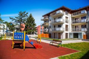 a playground with a slide and two benches in front of a building at Prestige Apartments Neptun Park in Gdańsk