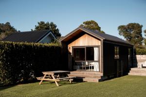 a small cabin with a picnic table in the grass at Tasman Holiday Parks - Hahei Beach in Hahei