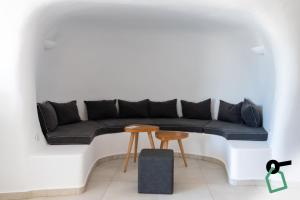 a black couch in a white room with a table at Hotiday Santorini Oia in Oia