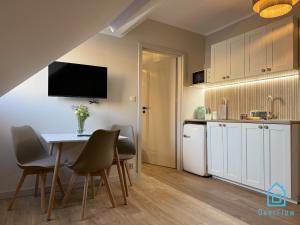 a kitchen with a table and chairs and a kitchen with white cabinets at Casa Verde Apartment at Old Town Gdańsk in Gdańsk