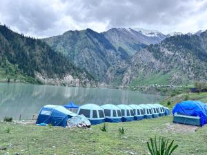 a row of blue tents next to a lake at Kishangangacampsgurez in Wāmpor