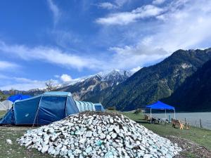 a pile of rocks next to tents and a lake at Kishangangacampsgurez in Wāmpor