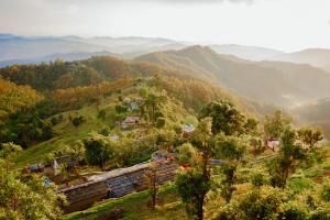 a village on a hill with mountains in the background at Jigyasa Homestay in Almora