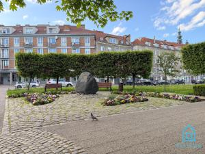 a bird sitting in a park with flowers and a rock at Casa Verde Apartment at Old Town Gdańsk in Gdańsk