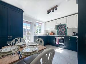 a kitchen with blue cabinets and a table and chairs at Little Tern in Snettisham