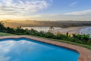 a swimming pool with a view of a beach at Shabby View Beach House in Southbroom