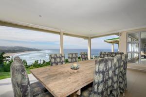 a dining room with a table and chairs and the ocean at Shabby View Beach House in Southbroom