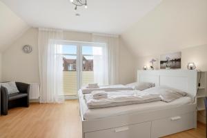 a white bedroom with a bed and a window at Meeresbrise in Norddeich
