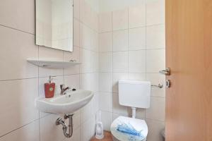 a white bathroom with a sink and a toilet at Meeresbrise in Norddeich +22 photos