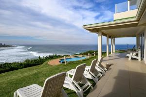 a row of chairs sitting on a porch overlooking the ocean at Shabby View Beach House in Southbroom +83 photos