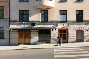 a woman walking down a street in front of a building at Bob W Stockholm Södermalm in Stockholm