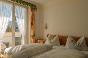 ein Schlafzimmer mit einem Bett mit Kissen und einem Fenster in der Unterkunft Hotel Roduna in Rodeneck + 34 Fotos