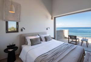 a bedroom with a bed and a view of the ocean at AÁSHNA Suites and Residences in Vaia +94 photos