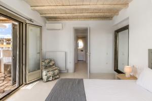 a bedroom with a bed and a chair at Your private Mykonos Villa in Kalafatis +38 photos
