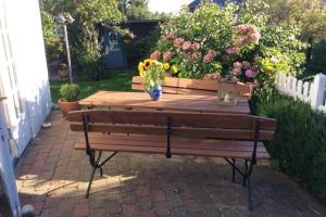 a wooden bench with a vase of flowers on it at Kapitänshaus, Hausteil in Oevenum
