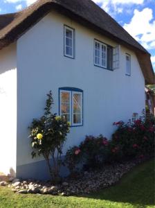a white house with flowers in front of it at Kapitänshaus, Hausteil in Oevenum