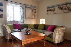 a living room with a green couch and a wooden table at Kapitänshaus, Hausteil in Oevenum