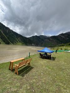 a picnic table and a blue tent next to a lake at Kishangangacampsgurez in Wāmpor +15 photos