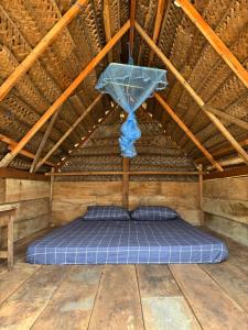 a bed in a straw roofed room with a blue canopy at Wana beach camp in Raddela