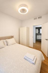 a white bedroom with a bed with towels on it at Apartamento Luxe Triana in Seville