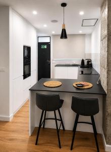 a kitchen with a black counter and two stools at Apartamento Luxe Triana in Seville +3 photos