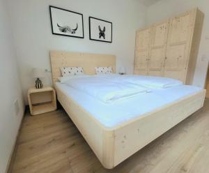 a bedroom with a large white bed with a wooden headboard at Rauchhof in Auer