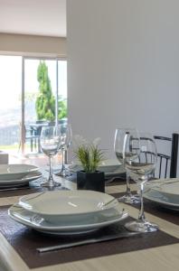 een tafel met borden en wijnglazen erop bij Hill Houses - Savoy Signature in Arco da Calheta