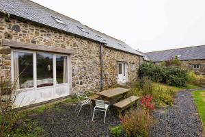 a stone building with a table and chairs in front of it at The Workshop- Eco Cottage by the Coastal Path in Goodwick