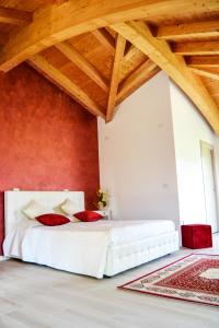カプリーノ・ヴェロネーゼにあるRama Relaisの白いベッドと赤い壁が備わるベッドルーム1室が備わります。