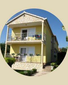 a yellow house with a balcony in a circle at Apartmani Marija - Vila Marija in Šilo