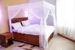 a bedroom with a canopy bed with white curtains at JK Maasai Hotel in Wasso