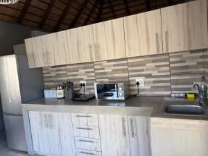 a kitchen counter with a sink and a microwave at Shiandi Cottage in Hoedspruit