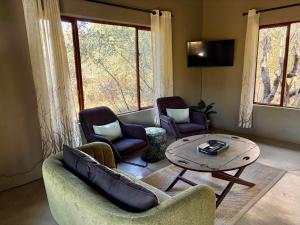 a living room with a couch and chairs and a table at Shiandi Cottage in Hoedspruit