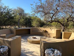 a patio with concrete furniture and trees in the background at Shiandi Cottage in Hoedspruit