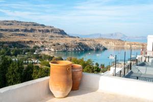 two large vases sitting on a balcony overlooking the water at Vasilikos Mansion - Captains Residences in Lindos