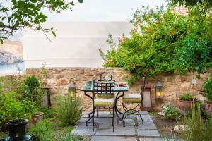 a patio with a table and chairs in a garden at Vasilikos Mansion - Captains Residences in Lindos