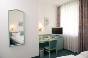 a room with a desk with a computer and a mirror at Hotel Till Eulenspiegel - Nichtrauchhotel - in Würzburg