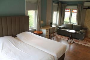 a bedroom with a bed and a couch and a desk at B&B de Pastorie Terneuzen in Terneuzen