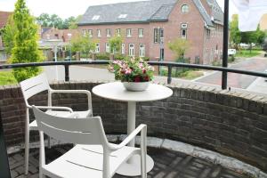 a table and chairs on a balcony with a vase of flowers at B&B de Pastorie Terneuzen in Terneuzen