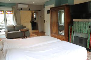 a bedroom with a white bed and a fireplace at B&B de Pastorie Terneuzen in Terneuzen