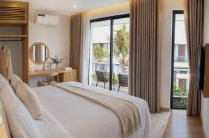 a bedroom with a white bed and a balcony at Sea La Vie Beachfront Villa - Bai Truong Beach Phu Quoc in Phú Quốc