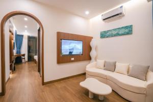 a living room with a couch and a tv at Sunset Samson Hotel in Sầm Sơn