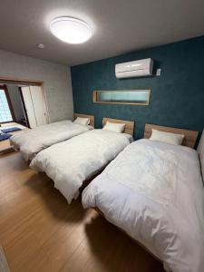 three beds in a room with a blue wall at 和風アンドラン in Minamiawaji