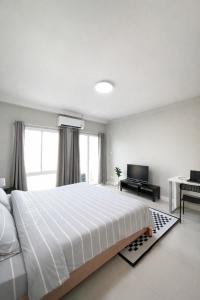 a white bedroom with a large bed and a television at Mayeen cat hotel in Chiang Mai