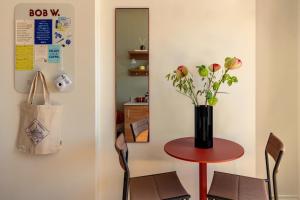 a red table with a vase of flowers on it at Bob W Stockholm Södermalm in Stockholm