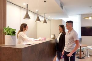 three people standing at a counter in an office at Hotel Centrale in Nago-Torbole
